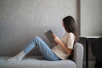 A woman with long hair is deeply focused on reading a book indoors, surrounded by a calm and...