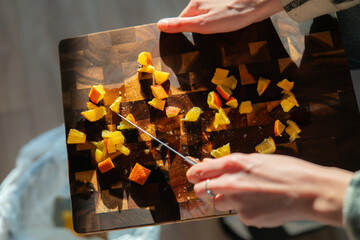 Individual prepares vegetables on a cutting board, efficiently wiping peelings and scraps directly into a waste bin nearby.