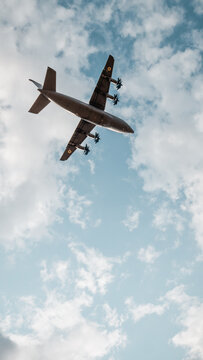 Looking up at the underside of An-70. Vertical image of a grey four-engined cargo plane against cloudy sky. Hostomel, Ukraine - August 22 2021.