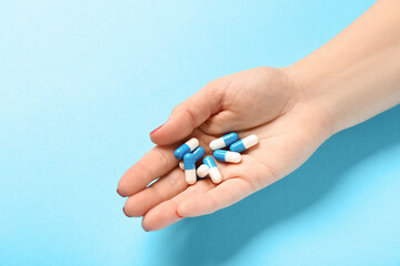 Female hand and pills on blue background