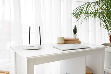 Workplace with laptop and wi-fi router in room