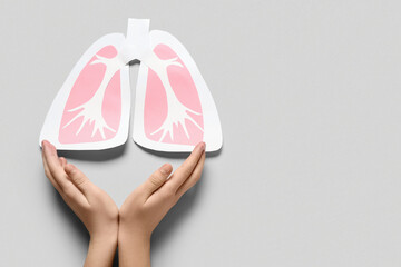 Female hands with paper lungs on grey background