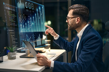 Professional Analyst Examining Business Data On Screen In Modern Office During Nighttime