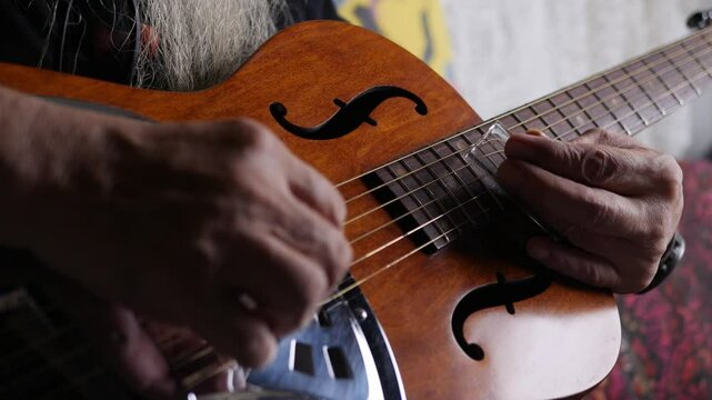 Male musician hand play Vintage Resonator acoustic dobro blues slide guitar.