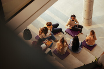 University students listening to teacher explaining lesson in modern building