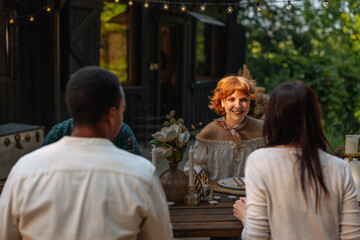 Cute redhead girl sitting at a wooden table with her friends