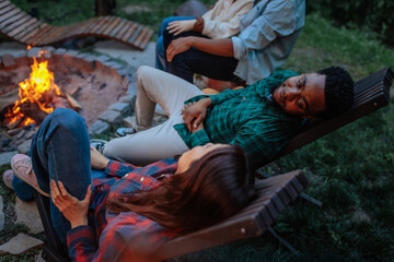 Two people talking while lying next to a burning fire pit