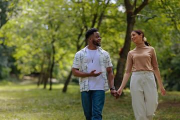 Fototapeta premium A couple walking through a park holding hands