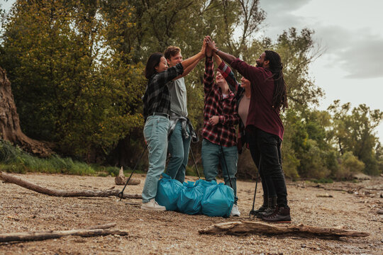 Volunteers joining hands after collecting trash on riverbank