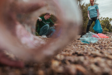 Shot from a plastic bottle perspective of volunteers picking up waste