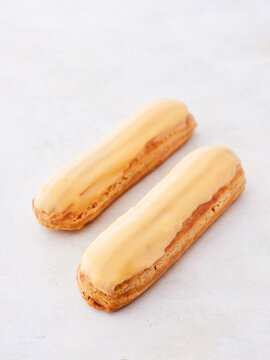 Two elegant eclairs sit side by side, adorned with a glossy caramel glaze. The setting is inviting, perfect for a sweet treat while enjoying a tranquil Parisian afternoon
