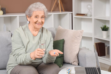 Senior woman with pills and glass of water sitting on sofa at home