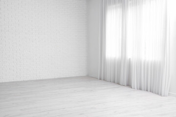 View of empty room with laminate floor and window curtain