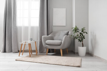 Interior of light living room with grey armchair and tables