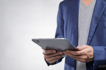 Person Holding Tablet in Stylish Outfit with Neutral Background © AK ST