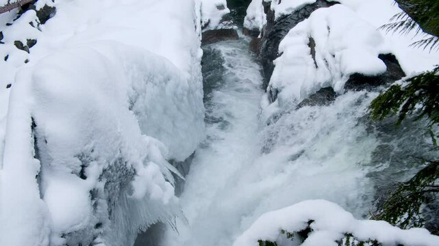 Snow Covered Rocky Canyon with Waterfall Below Icicles