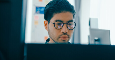Closeup young adult Asia male freelance eyeglasses typing write prompt AI bot IT app program nomad, video game, terminal with coding, user interface, designer, big data center on desktop computer.