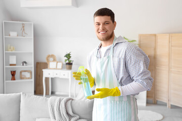 Young bearded man with spray bottle of detergent at home