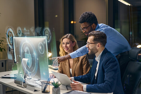 Team collaborating on cybersecurity solutions, analyzing futuristic hologram interfaces in office setting.