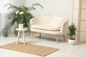 Stylish interior of light living room with comfortable sofa and beautiful houseplants