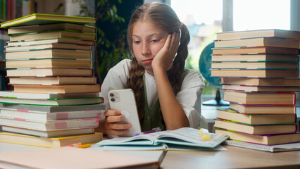 Little girl Caucasian bored school child kid teenage learner unmotivated student pupil schoolgirl boredom use mobile phone chat online smartphone social media education lesson indoor classroom library