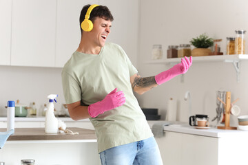Young man with headphones cleaning in kitchen