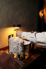The hands of a male waiter use a commercial drying machine to polish a wine glass in close-up