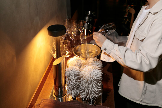 Male waiter looking at wine glass after using a commercial drying machine to clear and polish it - Powered by Adobe