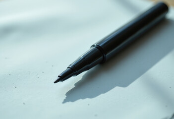 A close up shot of a glossy, teardrop shaped marker, casting a subtle shadow on a textured paper surface