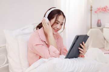 Beautiful young woman playing with digital tablet on bed