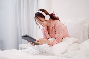 Beautiful young woman playing with digital tablet on bed