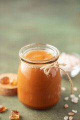Glass jar with salted caramel and spoon on the table