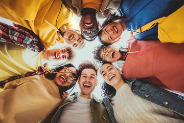 Multi racial group of friends standing in circle smiling at camera together - Group of young people...