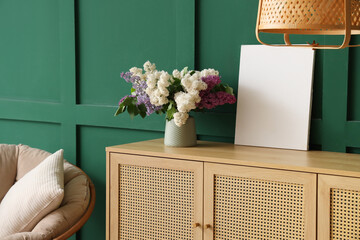Armchair with pillow and wooden cabinet near green wall in living room