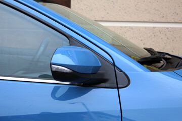 Blue Rear view mirror new car. Side rear-view mirror on a modern car. Close up rearview mirror new car. Blue car side mirror in exterior. 