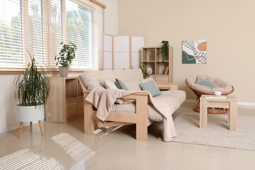 Interior of stylish living room with comfortable sofa, armchair, coffee table and folding screen