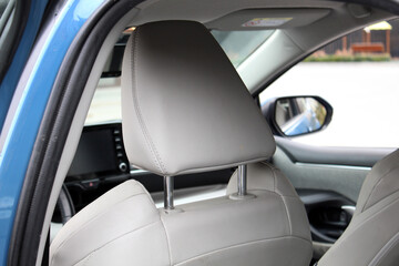 Fototapeta premium Close-up white headrest drivers seat made of genuine textile. Driver seat of a new vehicle. New light textile car interior. Beige textile car seats in the expensive car.