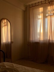 Bedroom interior with mirror and curtains in sunlight. Good morning. 
