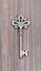 Ornate silver skeleton key on wood background