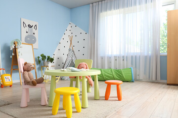 Interior of modern playroom in kindergarten with table, chairs and toys