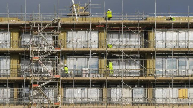 Building workers on scaffolding.
Telephoto shot of workers on scaffolding on a block of flats.