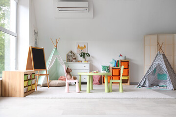Interior of light playroom with toys, teepee and chalkboard in kindergarten © Pixel-Shot