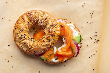 Lox bagel. A sandwich with smoked salmon and fresh vegetables on baking paper, overhead flat lay shot
