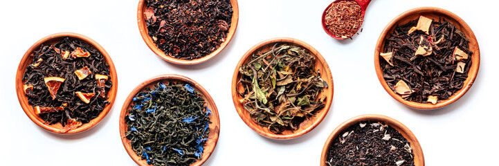 Loose tea leaves with herbs, flowers, and fruit panorama. Black, green, and white teas, and infusions, overhead flat lay panoramic shot on white
