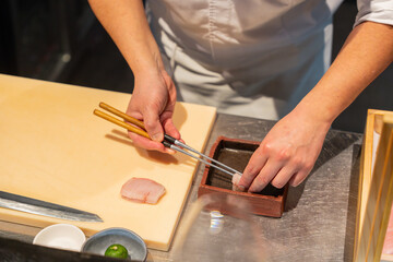 Chef talentueux préparant des sushis raffinés dans un restaurant haut de gamme, mettant en avant des ingrédients frais et de qualité.