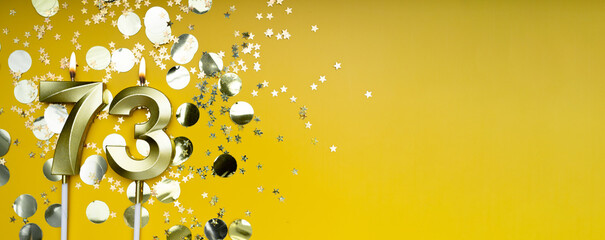 Seventy-three years birthday. Number 73 golden celebration candle. Yellow festive background. Concept of celebrating birthday or anniversary.
