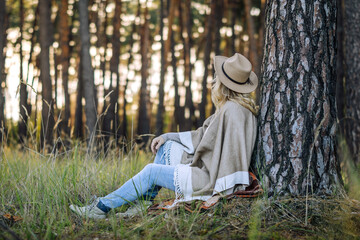 Relaxation and forest bathing. Woman with poncho and hat spending time in nature for mental...