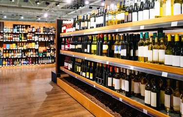 Liquor store background with wine bottles on shelves in wine shop.
