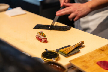 Chef talentueux préparant des sushis raffinés dans un restaurant haut de gamme, mettant en avant des ingrédients frais et de qualité.