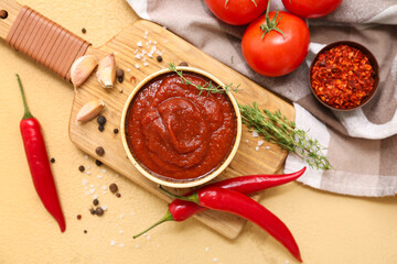 Bowl of chili sauce and different ingredients on yellow background